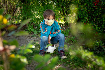 Child with face mask is playing with a ball