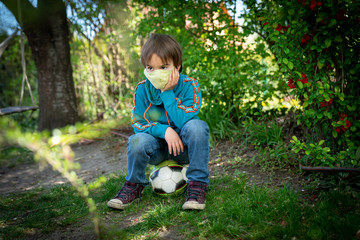 Child with face mask is playing with a ball