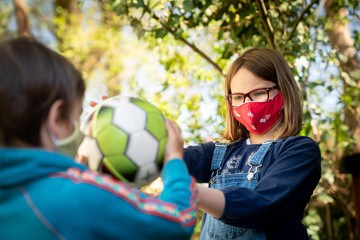 Two children with a face mask playing ball