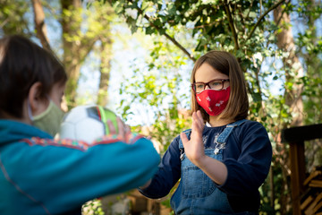 Two children with a face mask playing ball