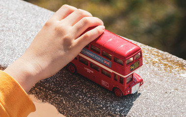 Hand of Child Playing with a Red Double-decker Bus Toy