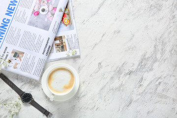 Cup of coffee and newspapers on light background