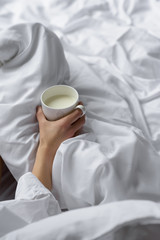 woman drinking milk in white bedding