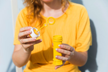 Fototapeta premium Close-up woman with bubbles maker wearing yellow dress