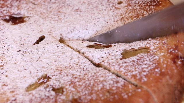 Knife cuts apple pie to pieces