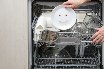 Fine washed dishes in the dishwasher. Integrated Dishwasher with white plates front vew and happy...