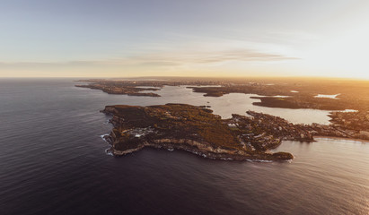 Obraz premium XXL panoramic sunset aerial drone view of North Head, a headland in Manly, Sydney, New South Wales, Australia. Manly Beach on right. Sydney Harbour with South Head, CBD & Harbour Bridge in background.