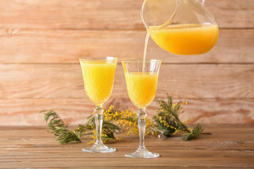 Preparing of tasty mimosa cocktail on wooden background