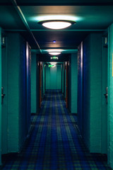 Dark corridor with illumination on ceiling. Tunnel view of empty hotel corridor in night time, toned