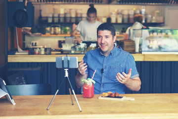 Social media influencer or food blogger creating digital marketing content by filming video inside...