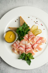 Plate with thinly sliced fat and mustard served with greens