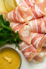 Plate with thinly sliced fat and mustard served with greens