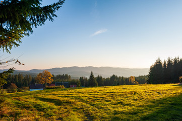 Warm light sunset panorama view of  Beskydy mountains with fog in the valley and blue cloudless sky, beutiful sunny afternoon in Czech mountains, Beskid Slaski near Lysa hora mountain.