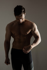 Fototapeta na wymiar Silhouette of a muscular athlete posing on a dark background