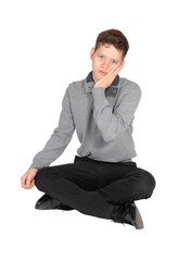 Teenage boy sitting on the floor with hand on his face