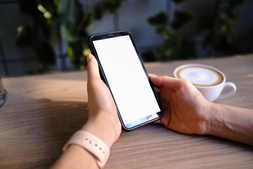 Mockup image of a woman holding and showing black mobile phone with blank screen in cafe.
