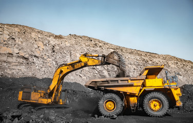 Obraz premium Coal loading at open mining site yellow truck industry