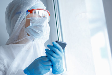 Tired look doctor woman biohazard looking out window, sleepless nights working in quarantine...