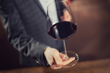 Waiter serves glass of red wine in restaurant, dark background