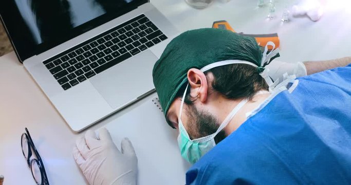 Giovane medico o infermiere dorme sulla scrivania dell'ospedale dopo un turno massacrante in terapia intensiva a curare i pazienti affetti da coronavirus.