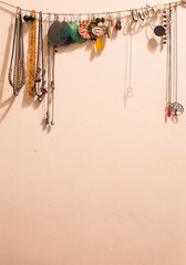 Colored earrings and necklaces 
hanging on the wall with a string of rope.
