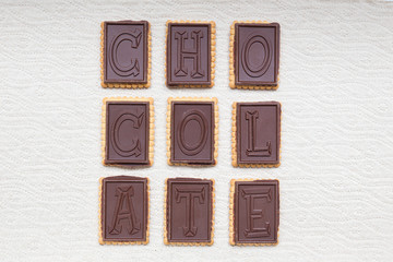 Rectangular frame of dark chocolate biscuits composing the word "chocolate". Abstract eco paper background. 