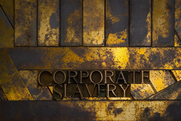Photo of real authentic typeset letters forming Corporate Slavery text on vintage textured grunge copper and gold background