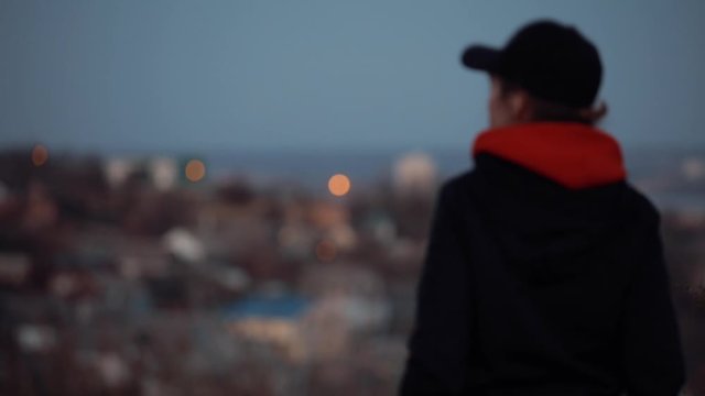 Pretty woman in a cap turn face standing in evening cityscape