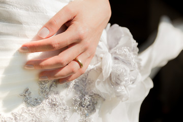 Wedding day. Close up to a bride ring during cerimony. White dress and black background. 