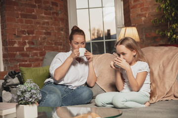 Tea drinking, talking. Mother and daughter during self-insulation at home while quarantined, family time cozy, comfort, domestic life. Cheerful, happy smiling models. Safety, prevention, love concept.