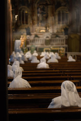 Nuns in white dress praying in Cottolengo's church with sunlight through the window