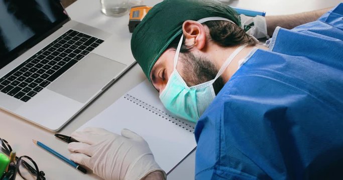 Giovane medico o infermiere dorme sulla scrivania dell'ospedale dopo un turno massacrante in terapia intensiva a curare i pazienti affetti da coronavirus.