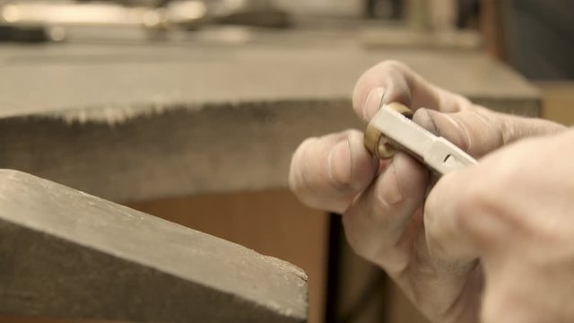 goldsmith sizes a golden ring  with a plier