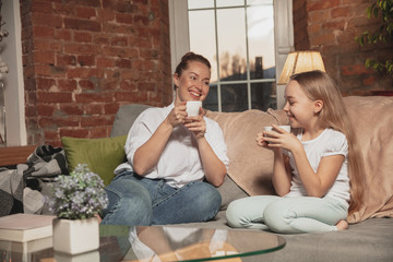 Tea drinking, talking. Mother and daughter during self-insulation at home while quarantined, family time cozy, comfort, domestic life. Cheerful, happy smiling models. Safety, prevention, love concept.