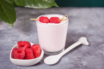 Natural homemade yogurt in a glass jar with fresh raspberry on the concrete table. Breakfast concept.