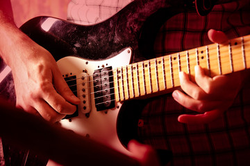 Life style image of close up young male guitarist hand, playing electric guitar