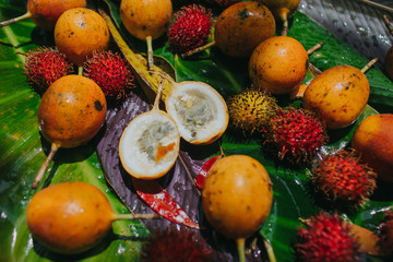Close-up of yellow passion fruit and lychee fruit on banana leaves