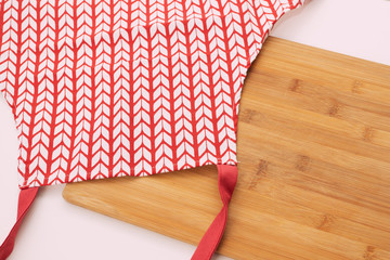 Obraz premium Red white apron and cutting board on a white table