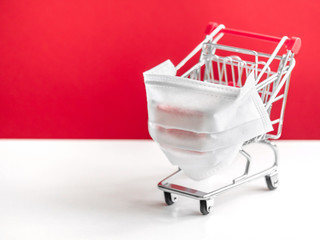 Shopping cart with protective medical mask against coronavirus. Safe and online shopping on...