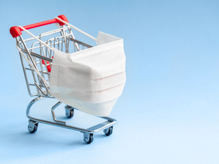 Shopping cart with protective medical mask against coronavirus. Safe and online shopping on...