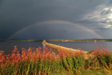 Rainbow in front of a dark, stormy sky over the Fornby pier at Siljansnäs, Siljan lake, Sweden.