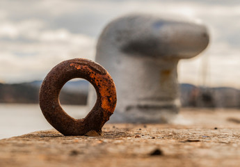 Rusty iron mooring ring by the sea - obrazy, fototapety, plakaty