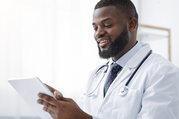 Smiling african american medical doctor holding digital tablet