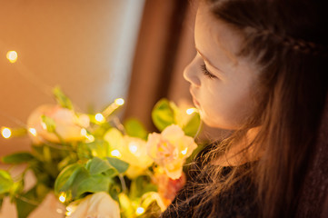 Portrait of a beautiful girl with a bouquet of color, bokeh and light from a garland