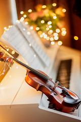 Musical instruments: the violin lies on an electronic piano, the background is bright bokeh. Music...