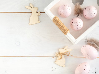 Fototapeta na wymiar Easter flatlay with pink eggs and wooden bunnies on white table. Top view with copy space for text.
