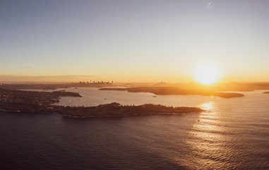 High resolution panoramic sunset aerial drone view of famous Sydney Harbour with the city centre in the background. South Head, a headland to the north of Watsons Bay suburb, in the foreground.