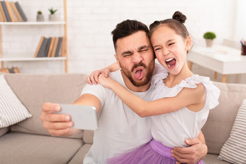 Happy father and child making selfie on cellphone at home