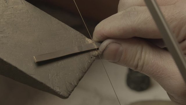 Close-up of a goldsmith sawing a piece of gold
