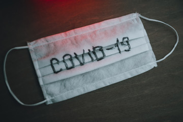 medical mask with the inscription "COVID-19" on a dark background with red light